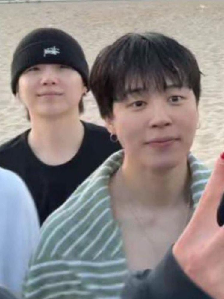 Yoongi with his black beanie and black shirt looking like a dumpling and jimin looking like a pretty doll as usual but shirtless with a tower wrapped around him in the ot7 beach live 