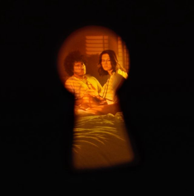 Selena and Benny peering through keyhole on a bed for I Said I Love You First album 