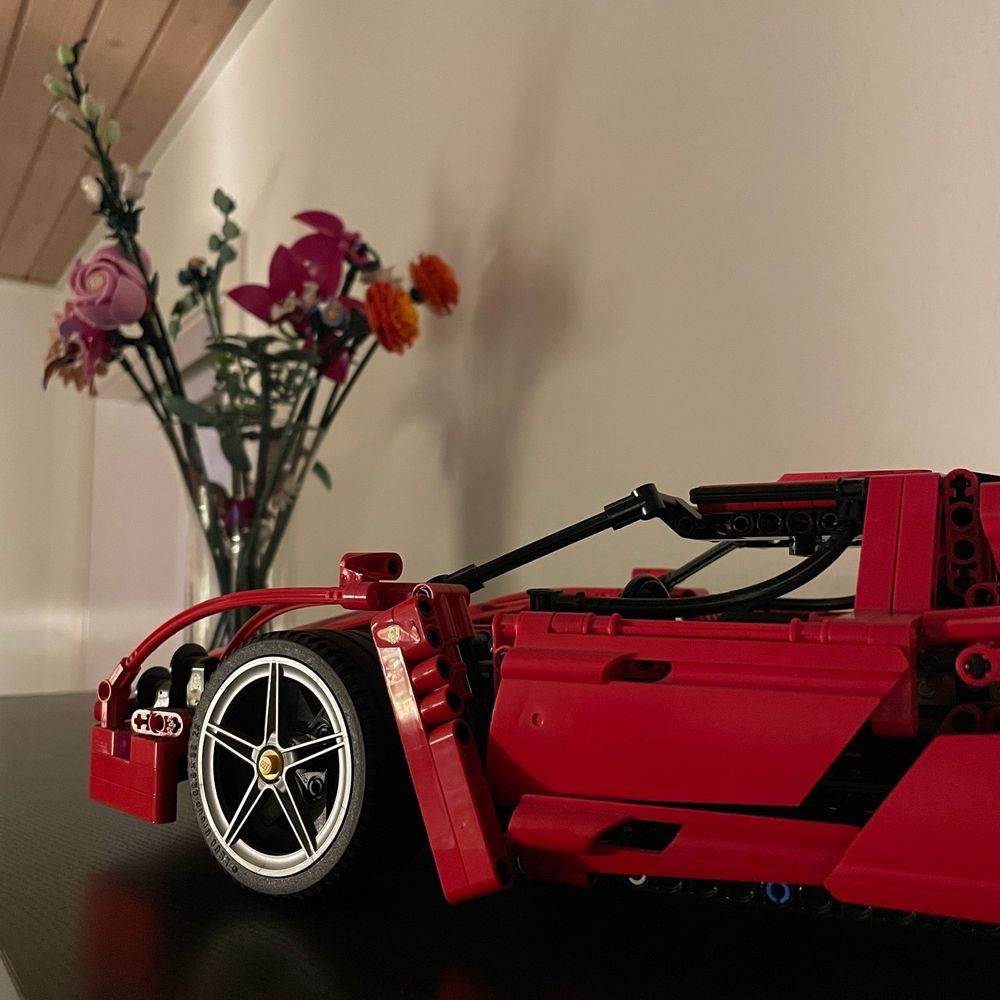 Shelf displaying a LEGO Ferrari Enzo model and a bouquet of LEGO flowers.
