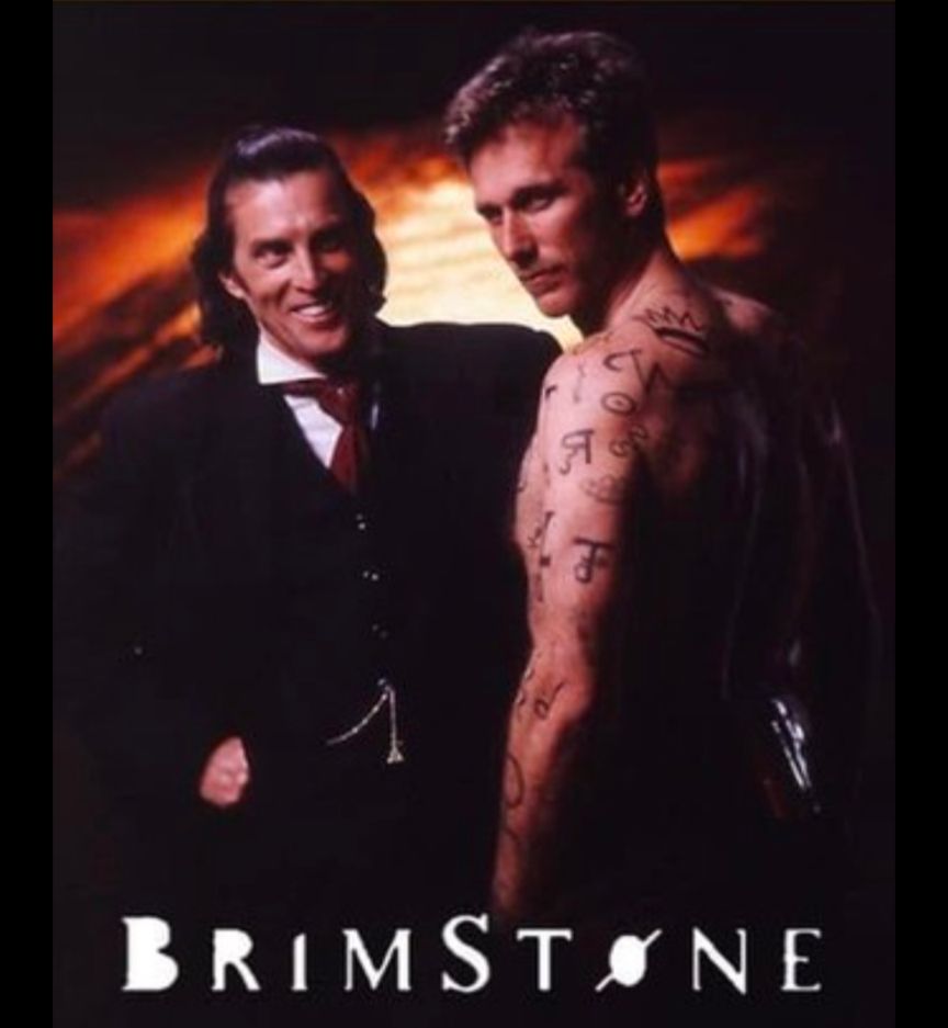 Two men, one the devil and the other a man covered in tattoos.