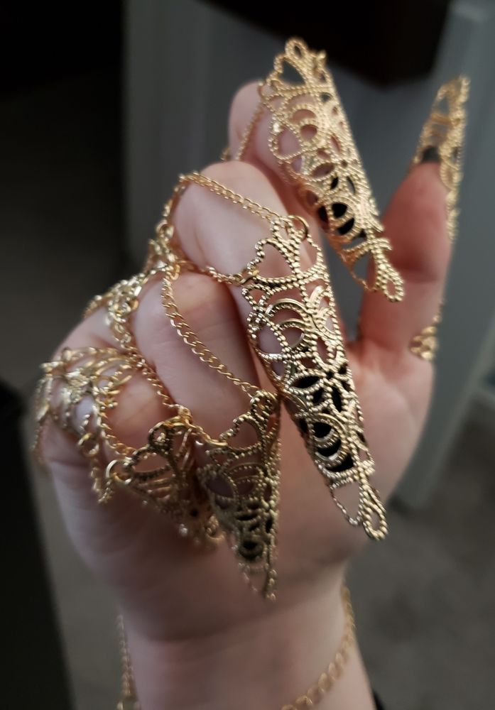 Photo of a hand with an intricate gold finger and nail bracelet. This image shows off the claw-like pieces covering the nails.