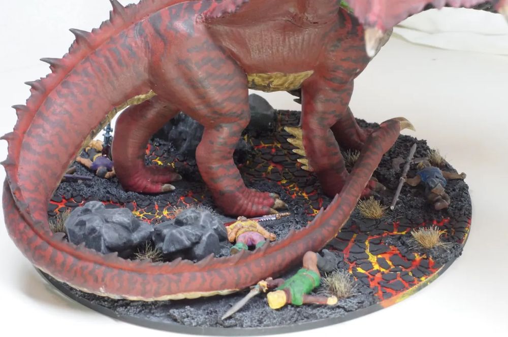 detail of the Tiamat base. four fallen adventurers are visible. The base has multiple channels of lava flowing through an ashy landscape as well as numerous dead plants