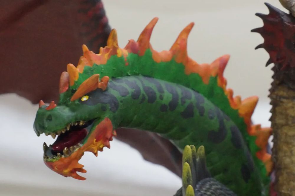 Side view of the green (poison) head. The head is green with black spots and mix of red/orange/yellow detailing that (hopefully) suggests a poison dart frog or other poisonous reptile