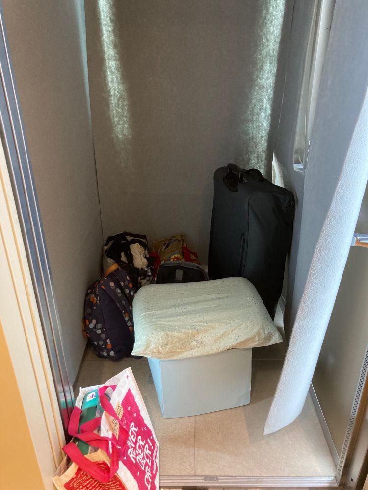 Un ascenseur plein: valise, sacs à dos, sacs de courses, une boîte carrée en tissu avec un oreiller par-dessus
