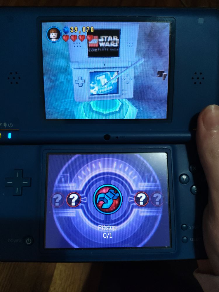 A picture of a DSi XL blue edition playing Lego Star wars tcs. The minigame menu is opened to the only currently unlocked minigame: "Pitstop"