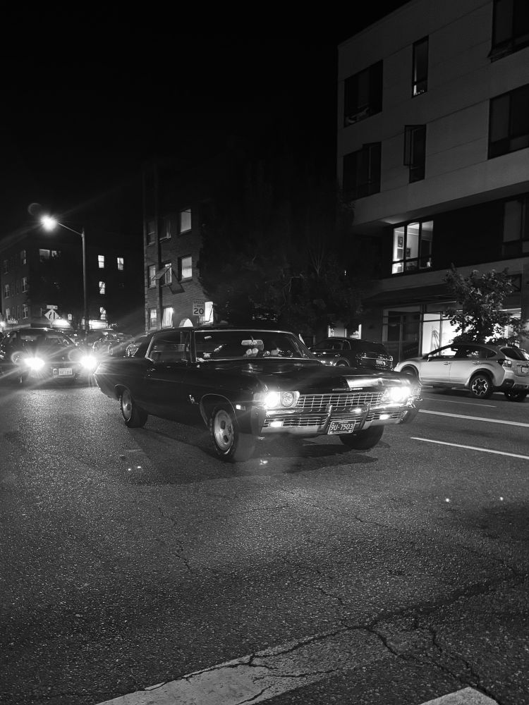 Black and white photo of a car at an intersection 