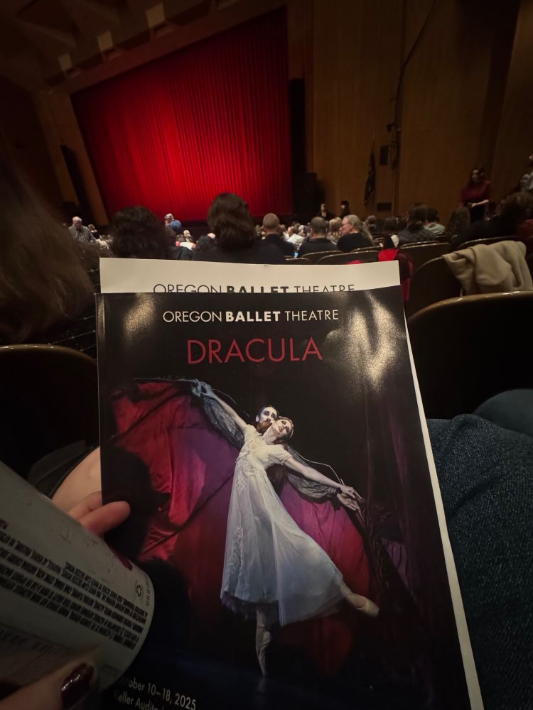 A photo of the Dracula ballet program with people in seats in front of a curtained stage in the background. 