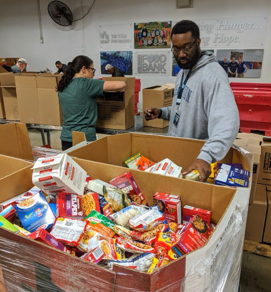 Volunteers distribute non-perishable food, out of boxes, at a food bank.