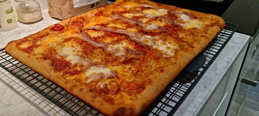 A grandma style sourdough pizza with a cherry tomato sauce, local bacon and mozarella