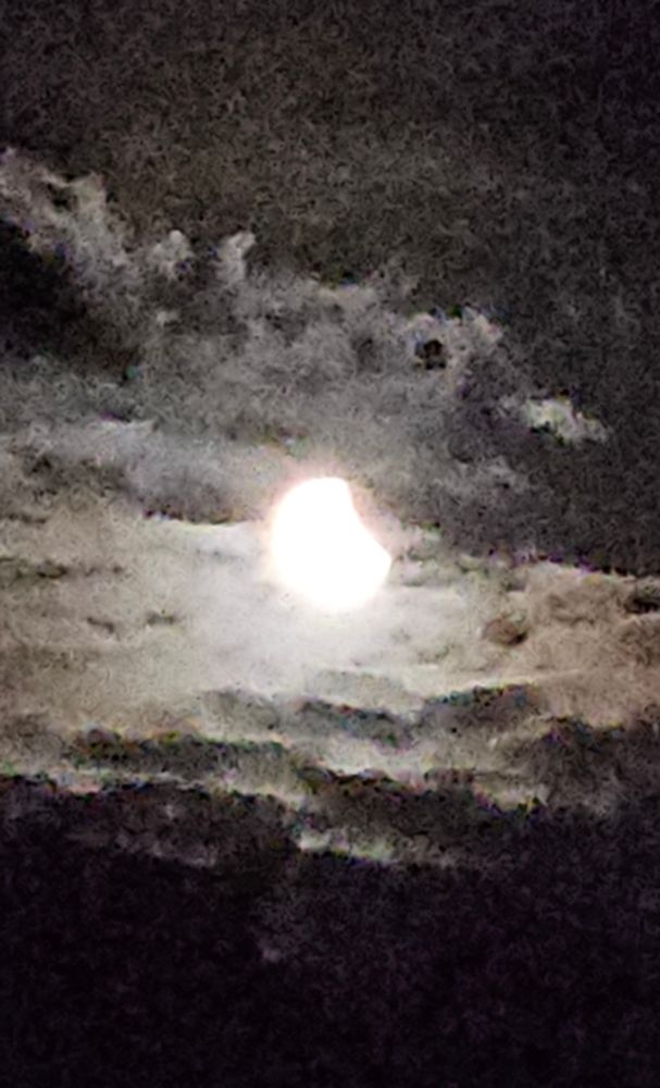 Grainy photo of moon showing a small part eclipsed uppdr right