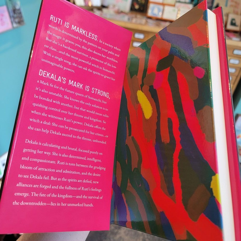 Ruti is Markless. In a society where worth is determined by the mark on your palm and the magic it grants you, this also deems her worthless. Except she’s also a hardened survivor, a protector of the Markless…and the most powerful witch in Somanchi. With a single song, she can pray to the many gods for unimaginable powers.

Dekala’s Mark is strong, a Mark fit for the future queen of Somanchi, but it’s also unstable. She knows the only solution is to be bonded, but she also knows that this would mean relinquishing control over her throne and kingdom. So when she is witness to Ruti’s power, Dekala offers the witch a deal: She can be prosecuted for her crimes…or she can help Dekala ascend to the throne, unbonded.