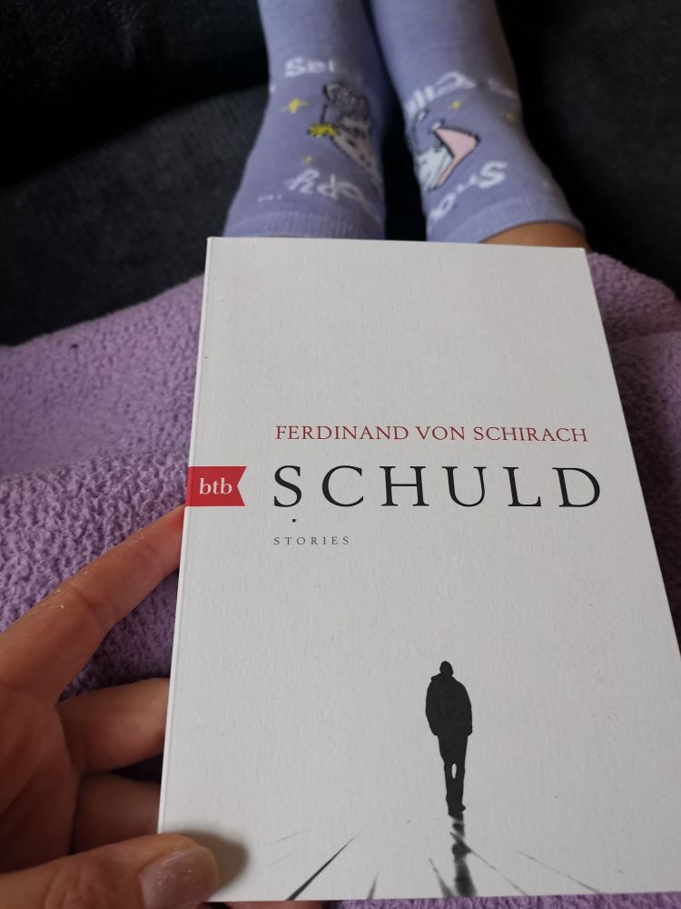 Ferdinand von Schirach's "Schuld" in meiner Hand
Man sieht noch eine fliederfarbene Decke und Snoopy Strümpfe fast im gleichen Fliederton