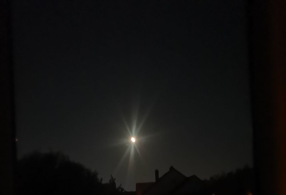 Mondschein am Nachthimmel Schatten von paar Häusern zu sehen 