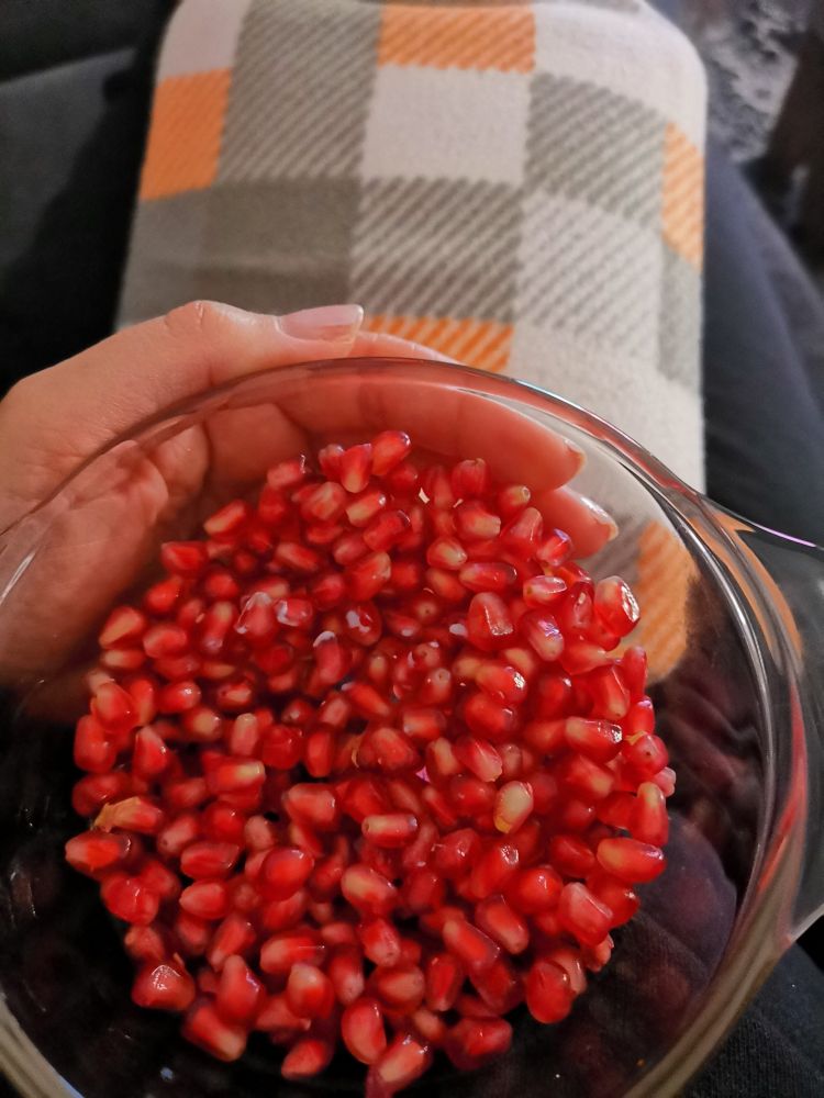 Granatapfelkerne in einer Schüssel auf meinem Schoß+ meine Wärmflasche