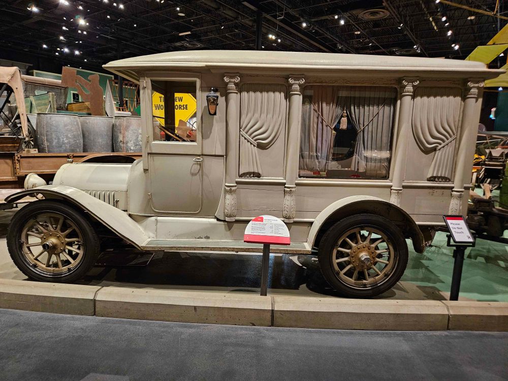 Museum exhibit of a 1916 Buick Hearse with carved curtains and columns 