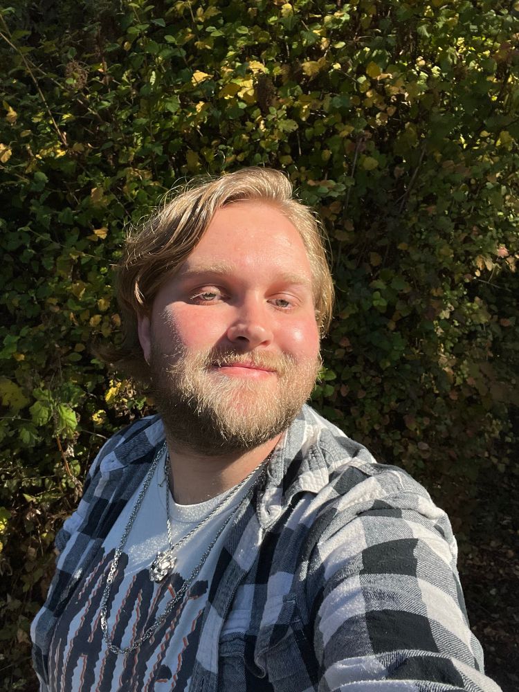 Selfie of me in a black and white flannel, SKA DREAM t shirt, and with two chains.