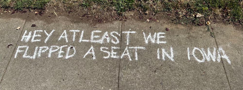 Chalk writing on sidewalk: Hey at least we flipped a seat in Iowa