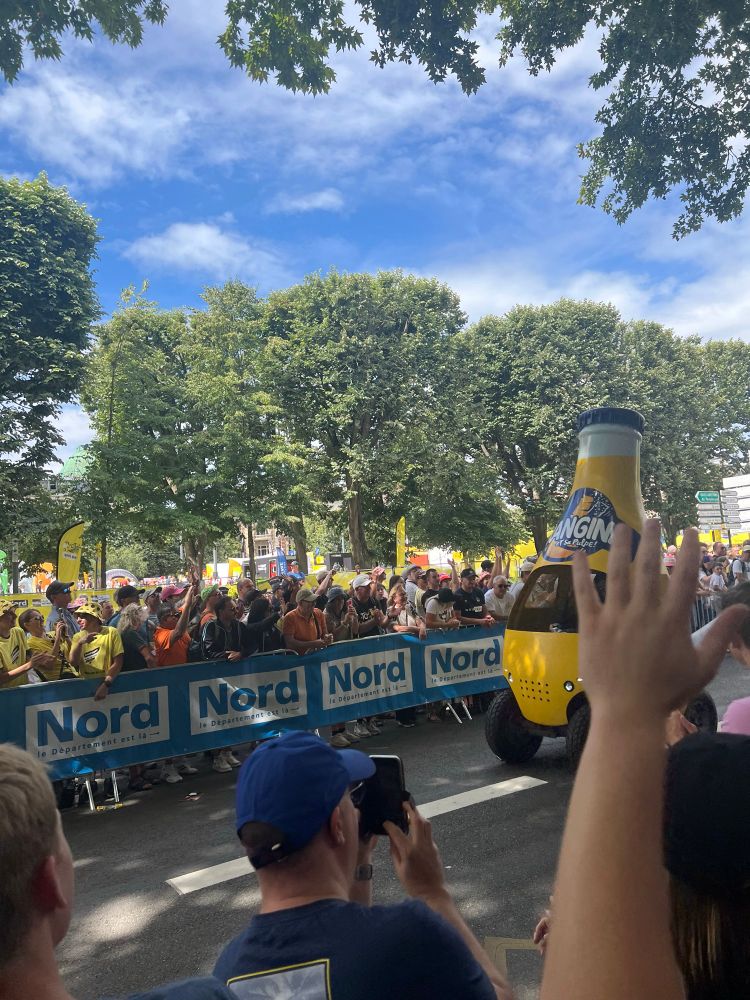 A hand sticks up from the crowd obscuring what would have been a decent shot of the Orangina car from the publicity caravan. 