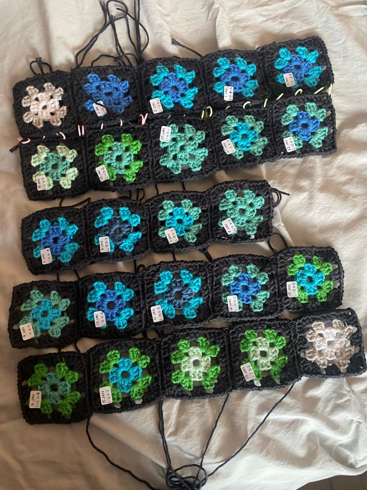 24 crocheted squares in different colours on a grey background.