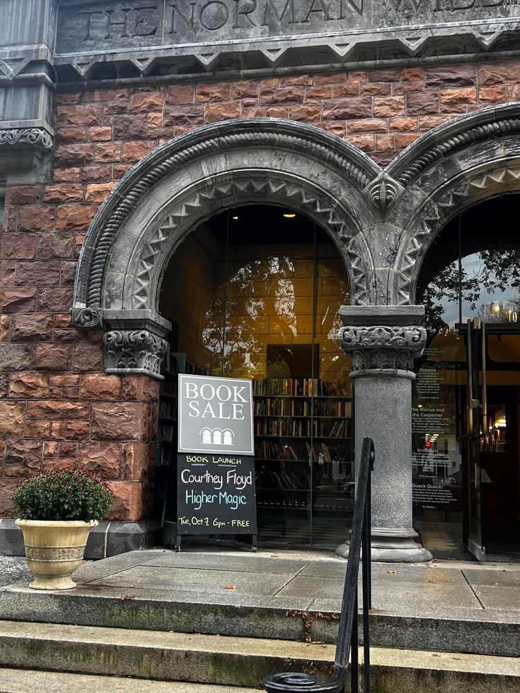 Beautiful brick building with arches, and a sign in front reading “Book Launch Courtney Floyd HIGHER MAGIC”