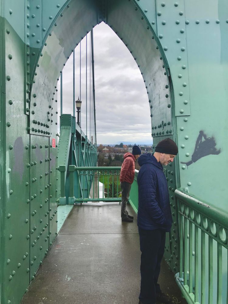 People stand under a green riveted steel arch