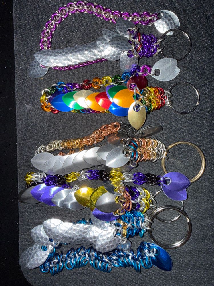 Chainmaille dragons in a variety of colors on a black background 