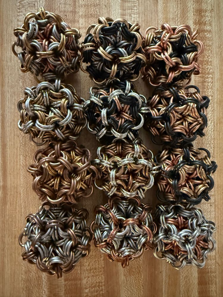 A series of chainmaille juggling balls on a wood background 