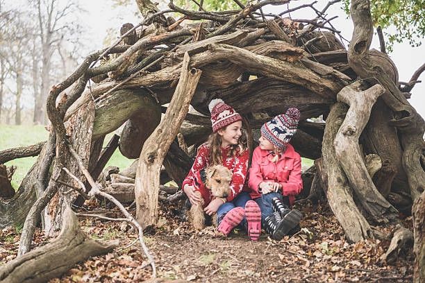 Children and a dog sheltering in a wooden den 