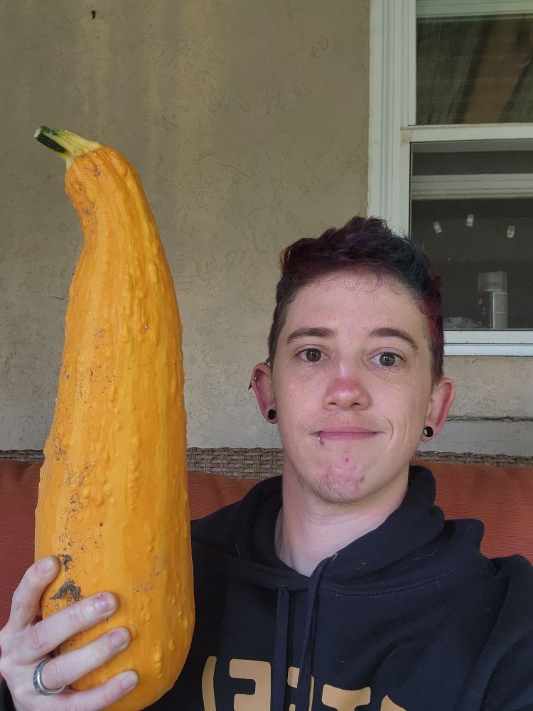 Selfie of me holding an enormous yellow squash from our garden. My head and torso for comparison 