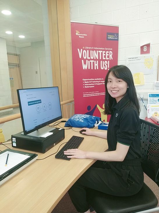 A volunteer in the Opportunities Room in Dundee Library, sits at a computer that is used to support people's digital skill development.