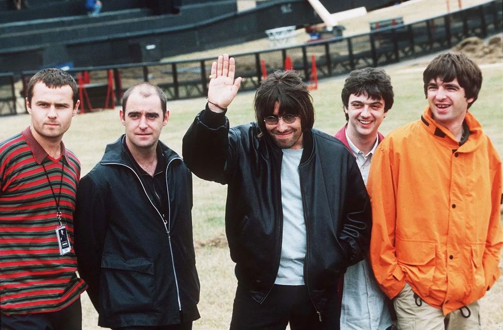 Liam Gallagher waving with the rest of Oasis. 1996.