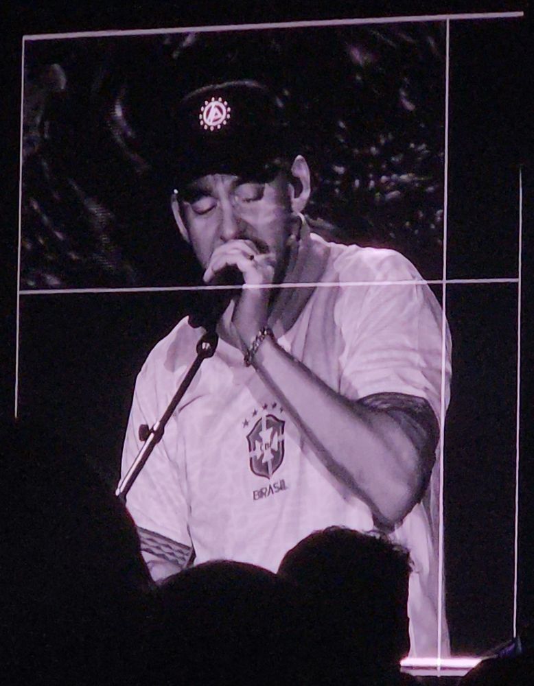 He's singing to the people while using the BRAZILIAN SOCCER TEAM T-SHIRT (and the same LP cap)