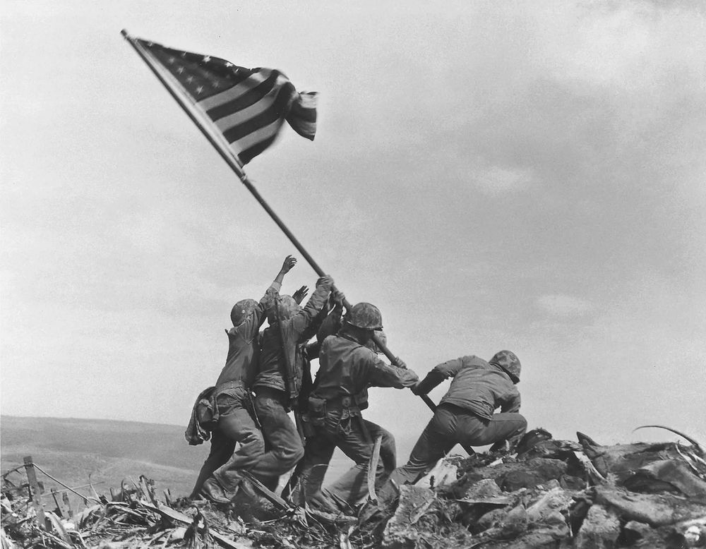 US Marines raising the American flag on a large mountain located on the island of Iwo Jima.