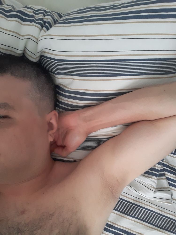 Homem branco de cabelo cortado bem curto deitado e mostrando o suvaco 