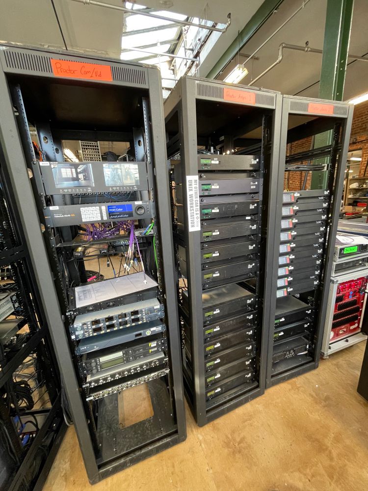 3 server racks of audio equipment. the center rack has a piece of paper taped to it that says “my other car is a sun microsystems unix workstation”