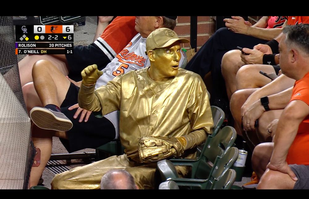 a man painted like a gold statue spectates an orioles game