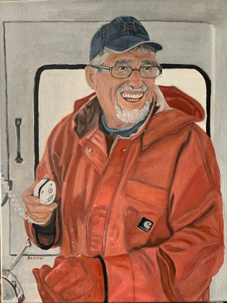 A lobster fisherman dressed in his orange rain gear, holding a radio mike. He has a big smile on his face. 