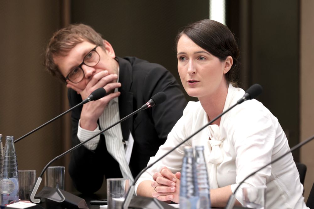 Miriam Seyffarth sitzt an einem Tisch und spricht in ein Mikrofon. Links neben ihr sitzt Leonhard Kugler und hört nachdenklich zu.