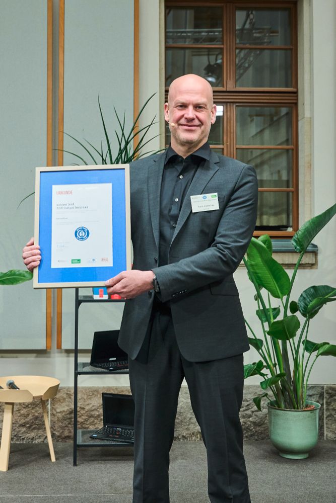Frank Karlitschek hält eine Urkunde mit dem Zertifikat Blauer Engel für Software in die Kamera