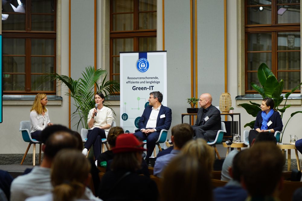 Auf einer Bühne sitzen für eine Podiumsdiskussion in einem Halbkreis Gitta Lauster vom Umweltbundesamt, Miriam Seyffarth von der OSBA, die gerade in ein Mikrofon spricht, René Pincus vom Bundesinnenministerium, Frank Kartlischek von Nextcloud und Anna Zagorski vom Umweltbundesamt.