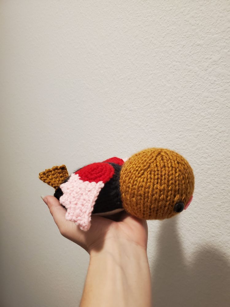 A side view of a knitted Spearow plushie