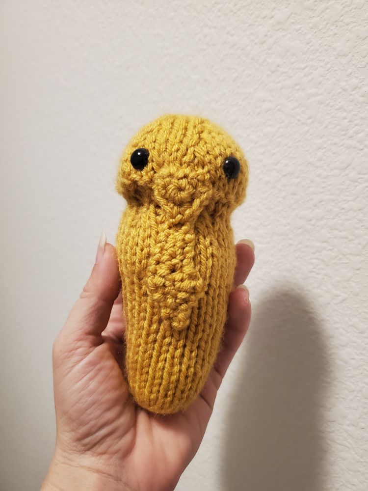 A front view of a knitted Kakuna plushie
