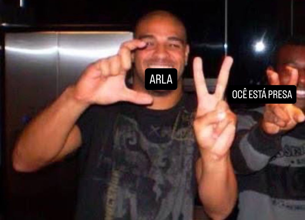 Adriano imperador fazendo a sigla CV com os dedos 

Complementei fazendo como se ficasse “Carla, você está presa”