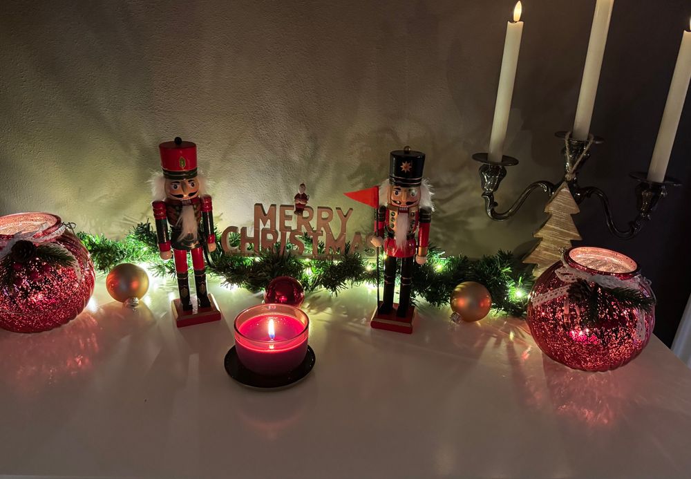 Weihnachtsdeko mit Kerzen, Nussknackern, Glaskugeln und Duftkerze. 
