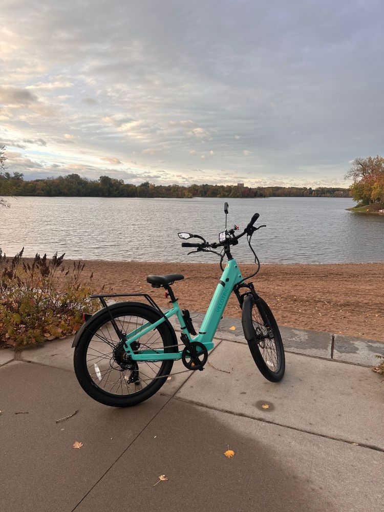 Cyan electric bike in front of a lake in Minneapolis, MN a little before sunset