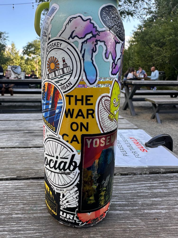 A “The War on Cars” podcast sticker on a water bottle with the letters “RS” covered by another sticker. Now it reads “The War On CA”