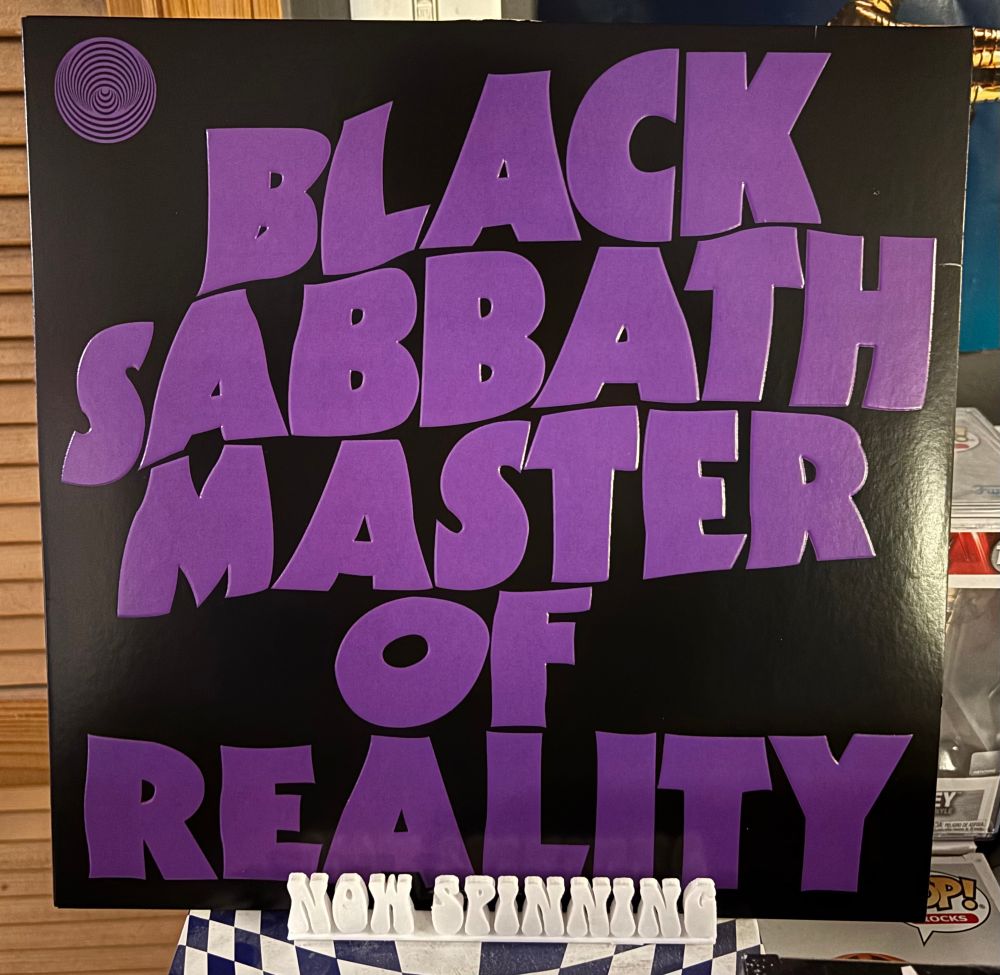 The cover of Black Sabbath's album Master of Reality displayed on a stand that says "now spinning".