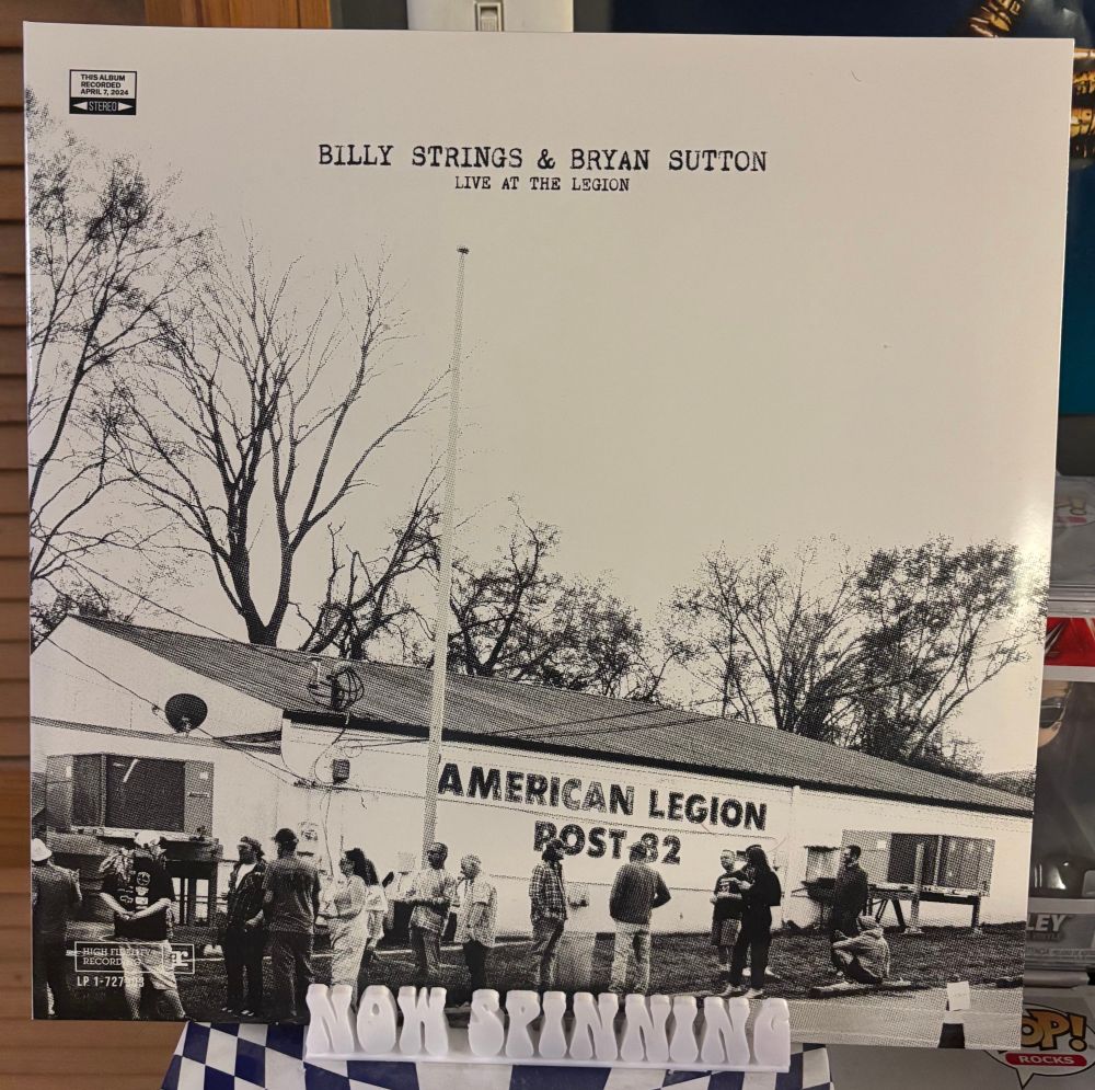 The cover of Billy Strings & Bryan Sutton's album Live at the Legion displayed on a stand that says "now spinning".
