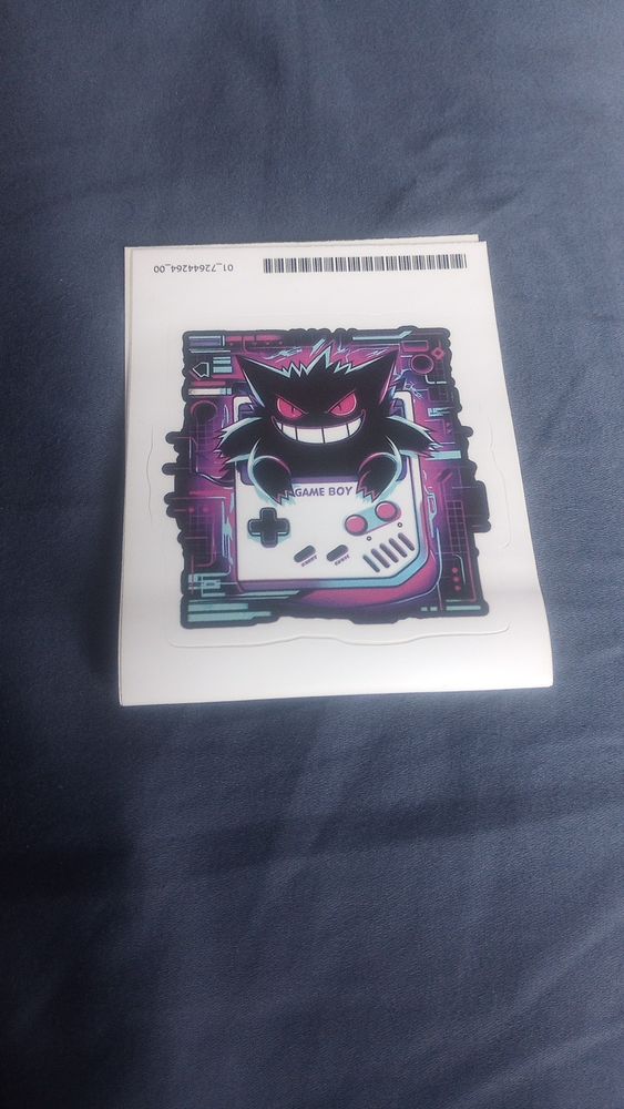A sticker with Gengar popping out of a white Game Boy Color. 