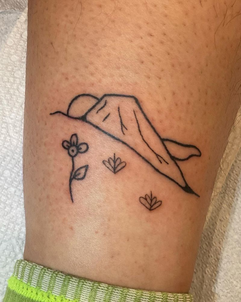 machine tattoo of a volcano view. foreground is filled with vegetation and flowers. 